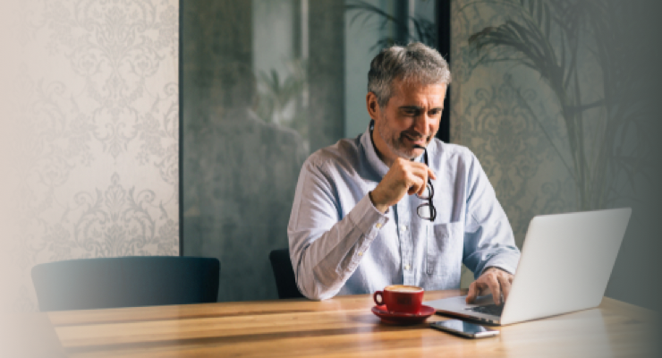 Homme d'âge mûr en train de lire une publication financière sur son ordinateur portable